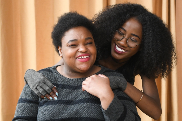 Close-up of two Black and disabled women smiling and holding hands - Disabled And Here